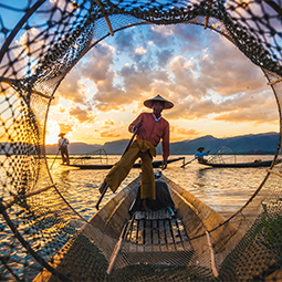 image d'un homme birman sur son bateau effectuant de la pêche lors du coucher de soleil