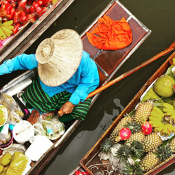 Image d'un homme ramant sur un bateau traditionnel Thaïlandais longtail transportant de la marchandises et nourritures dessus