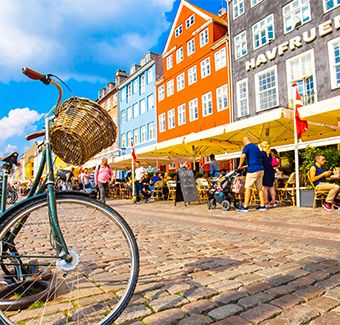 image d'un vélo en premier plan garé devant des maisons colorés située au port de Copenhague