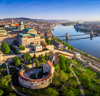 image avec une vue panoramique aérienne du Palais Royal de Buda avec le pont de la Chaîne Szechenyi, la basilique Saint-Étienne, le Parlement hongrois et l'église Matthias au lever du soleil