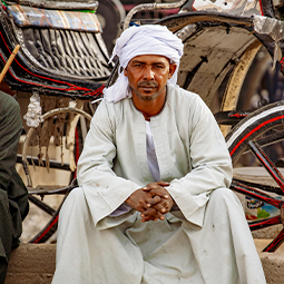 portrait d'un Égyptien en vêtements traditionnels assis devant des chariots qu'ils utilisent pour transporter les touristes de leurs croisières
