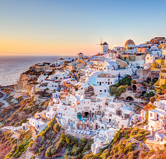 image de l'île de Santorin avec ses maisons blanches et bleues au sommet des falaises lors d'un coucher de soleil