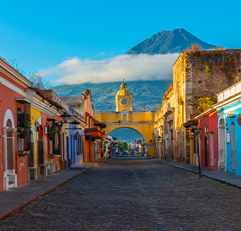 image d'un paysage urbain de la rue principale et de l'arc jaune de Santa Catalina dans le centre historique d'Antigua au lever du soleil avec le volcan Agua