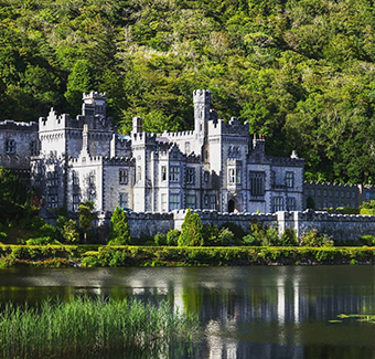 image du château de Kylemore avec son grand jardin derrière et son magnifique lac effet miroir