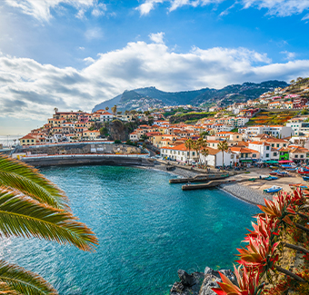 image de la ville de Funchal avec plein de maisons cote à cote au bord d'un port avec vue sur la mer et des montagnes