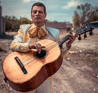 image d'un homme jouant de la guitare avec un costume de musicien Mexicain bleu et jaune