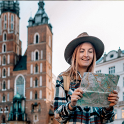 image d'une femme blonde aux cheveux courts avec un chapeau tenant une carte de localisation pour se repérer devant une cathédrale