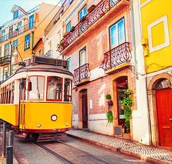 image d'un tramway jaune vintage circulant dans les rues de Lisbonne entre des maisons colorées