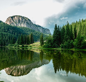 image d'un petit lac entouré de falaise et d'une large forêt lors d'un temps nuageux