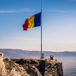 image du drapeau de la roumaine au toit d'une falaise devant la mer