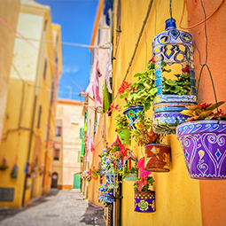 image d'une petite ruelle de maison orangées ayant chacune des pots de fleurs accrochées à leur murs