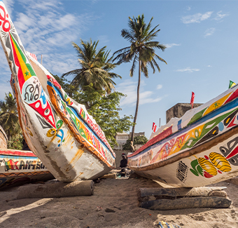 image de bateaux de pêcheurs en bois colorés sur une plage de sable au Sénégal