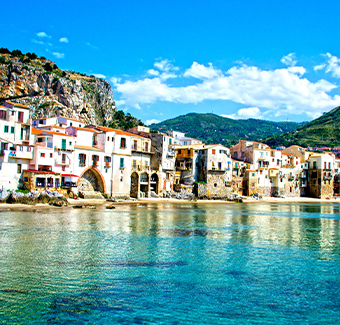 image de la côte de Cefalu avec sa mer, ses montagnes de verdures et ses maisons colorées et blanche