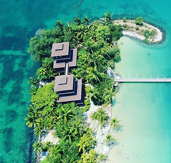 image d'une petite île habitée par une seule et belle grande maison entourée de verdures et d'eaux turquoises