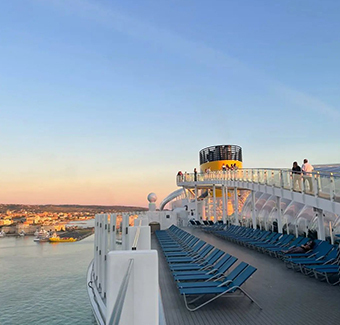 image du sommet du bateau de croisière lors d'un coucher de soleil avec pleins de transats alignés côte à côté