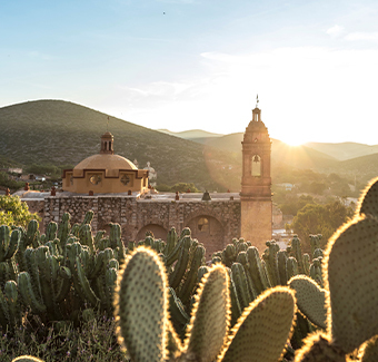 image de l'église Santo Domingo de Guzman avec pleins de cactus autour lors d'un coucher de soleil