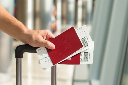 image d'une main tenant une valise et 2 passeports avec des cartes d'embarquements