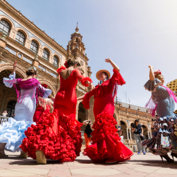 image d'un festival de danse avec des danseurs hommes et femmes pratiquant le flamenco avec des tenues de flamenco de couleurs vives et longues