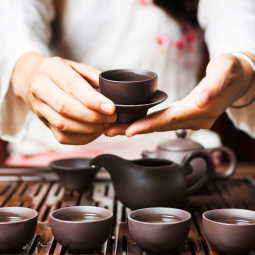 image d'une femme en kimono servant du thé dans des petites tasses en porcelaine marron